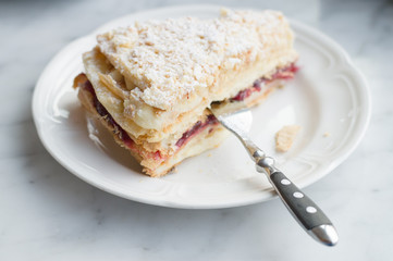 Slice of Mille Feuille cake on plate with fork, selective focus