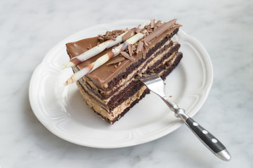 Slice of chocolate cake on plate with fork, selective focus