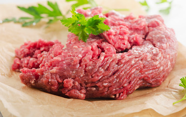 Raw ground beef meat with fresh herbs.