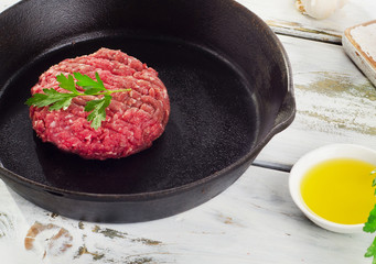 Raw beef burger patty on a pan.