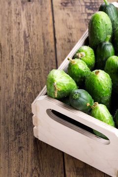 Cucumbers in a box on a wooden background. Copy space.