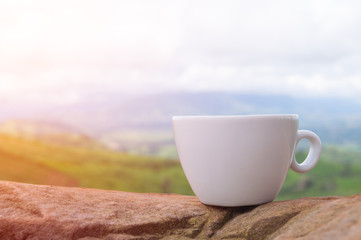 White coffee cup on the rock table with mountains view