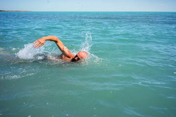 A man swims in the open sea