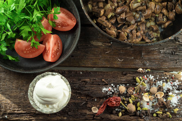 In the old vintage table are fried mushrooms, tomatoes and sour cream