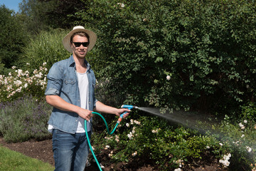 young handsome man is watering the plants