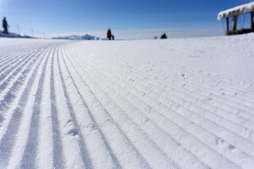 Fototapeta na wymiar Fresh snow groomer tracks on a ski piste