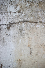 Vertical view of weathered concrete and stucco colonial wall in Asia. Horizontal crack crosses frame.