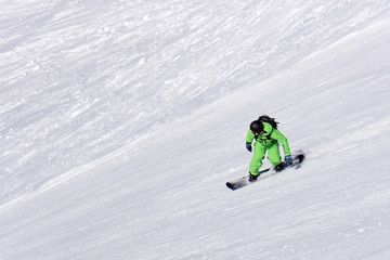 Fototapeta na wymiar Snowboarder going down the slope at ski resort.