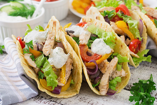 Mexican tacos with chicken, bell peppers, black beans and fresh vegetables and tartar sauce