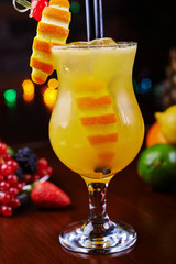 bright tropical alcoholic cocktail or lemonade with slices of orange and beautiful decoration on a table in a restaurant with backgrounds of bright colored lights. soft focus.