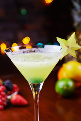 glass of bright tropical alcohol cocktail or lemonade with beautiful decoration on a table in a restaurant with backgrounds of bright colored lights. soft focus.