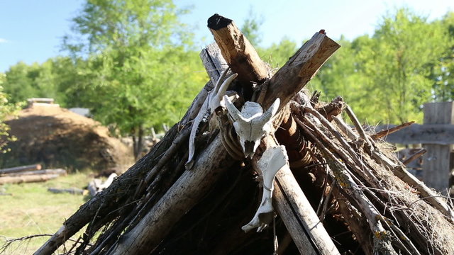 Ancient dwelling of the Stone or Bronze Age, it made out of tree branches and dry grass, the skulls and bones of animals hanging at the entrance
