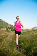 beautiful young woman runns cross country on a mountian path at