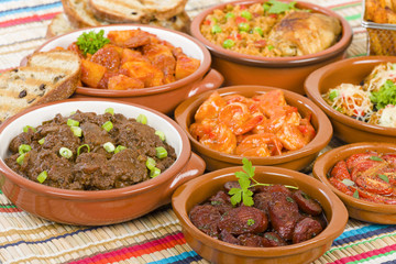 Tapas - Selection of latin dishes. Chorizo al vino, Higados de pollo, Chicken and chorizo, Tomates al ajillo, Arroz con pollo, Camarones enchilhados, Patatas a ala riojana and Stuffed mushrooms.
