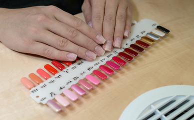 Woman at nail studio chosing color of nail polish after correcti