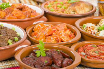 Tapas - Selection of latin dishes. Chorizo al vino, Higados de pollo, Chicken and chorizo, Tomates al ajillo, Arroz con pollo, Camarones enchilhados, Patatas a ala riojana and Stuffed mushrooms.

