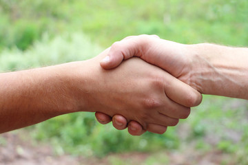 Suntanned male hands make handshake