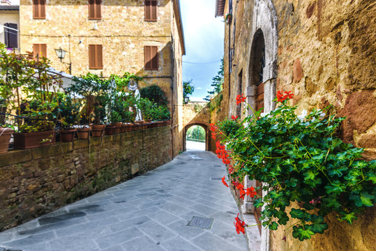 Fototapeta Street with flowers in the medieval Tuscan town.
