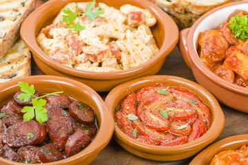 Tapas - Selection of latin dishes. Chorizo al vino, Higados de pollo, Chicken and chorizo, Tomates al ajillo, Arroz con pollo, Camarones enchilhados, Patatas a ala riojana and Stuffed mushrooms.
