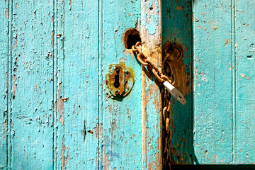 Old rusty padlock and chain on weathered textured door