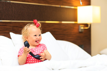 Fototapeta premium cute little girl taking on the phone in hotel room