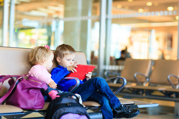 kids looking at touch pad while waiting in the airport