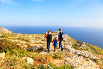 family with two kids hiking in summer mountains