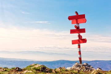 Red wooden direction arrows on top of the mountain, against blue clear sky.