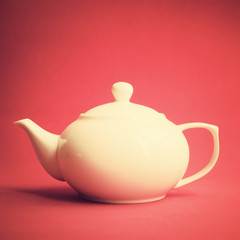 White teapot over red background