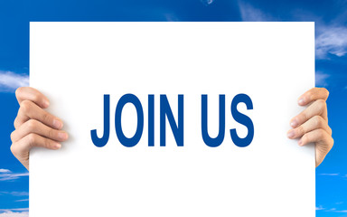 Hands holding a white board with the words join us, blue sky background
