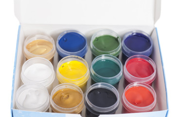 Open colorful cans of gouache paint in box