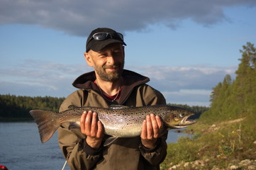 Fisherman caught a big salmon. Ponoy river, Kola Peninsula, Russia. 