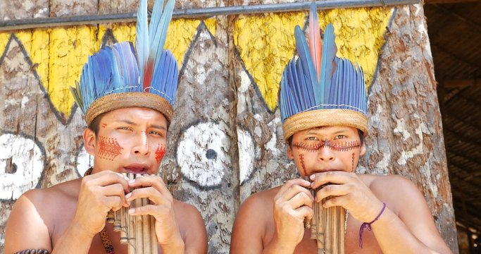 Native Brazilians playing wooden flute at an indigenous tribe in the Amazon