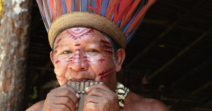 Native Brazilian playing wooden flute at an indigenous tribe in the Amazon