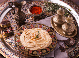 Hummus, chickpea dip, with rosemary, smoked paprika and olive oil in a metal  bowl .selective focus