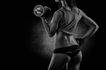 Brutal athletic woman pumping up muscles with dumbbells