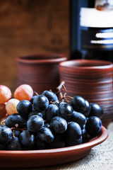 Blue and pink grapes on a clay plate and wine in rustic style, s