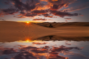 Fototapeta na wymiar Reflection of the sunset sky and sand dunes in the water.
