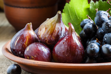 Ripe figs and grapes on a clay plate in a rustic style, selectiv