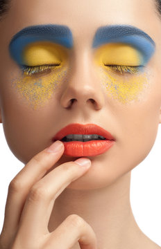 High fashion look, closeup beauty portrait of beautiful young woman model with bright makeup with perfect clean skin with colorful red lips and blue yellow eyeshadows, blue yellow color. High key.