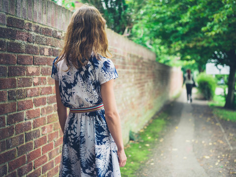 Young woman walking in the street by wall