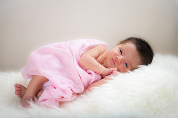 Obraz na płótnie Canvas Niña bebé recién nacido en calma relajada sobre una manta de pelo suave con muselina rosa