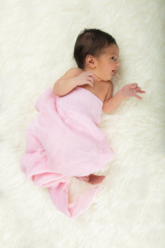Niña bebé recién nacido en calma relajada sobre una manta de pelo suave con muselina rosa