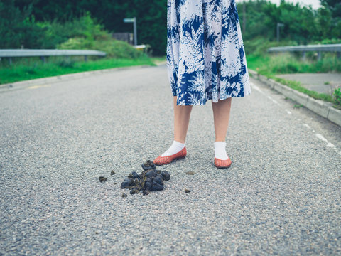 Woman standing in road by horse dung