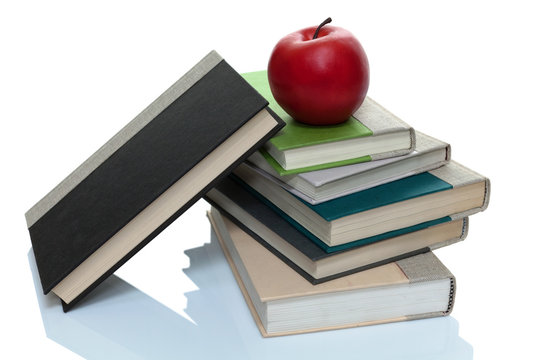 Hardcover books with a red apple on top with one leaning