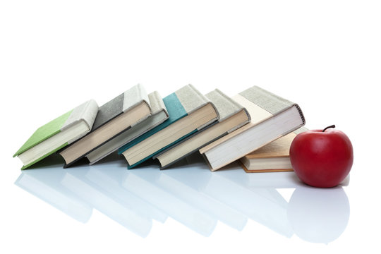 Books leaning on the side with an apple in front