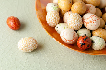 Japanese peanut snack mix in an orange bowl on crackled celedon glass