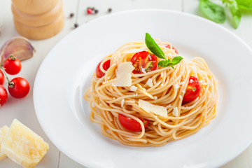 Italian spaghetti with tomato sauce, parmsesan cheese and basil on table