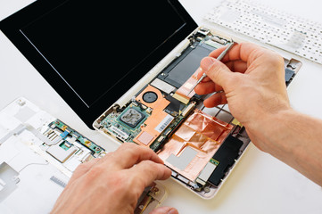 The engineer repairs the laptop (pc, computer) and the motherboa