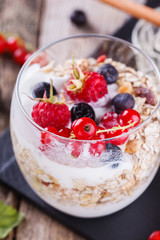 Breakfast with muesli, yogurt,honey and fresh berries in a glass on a wooden background. selective focus
